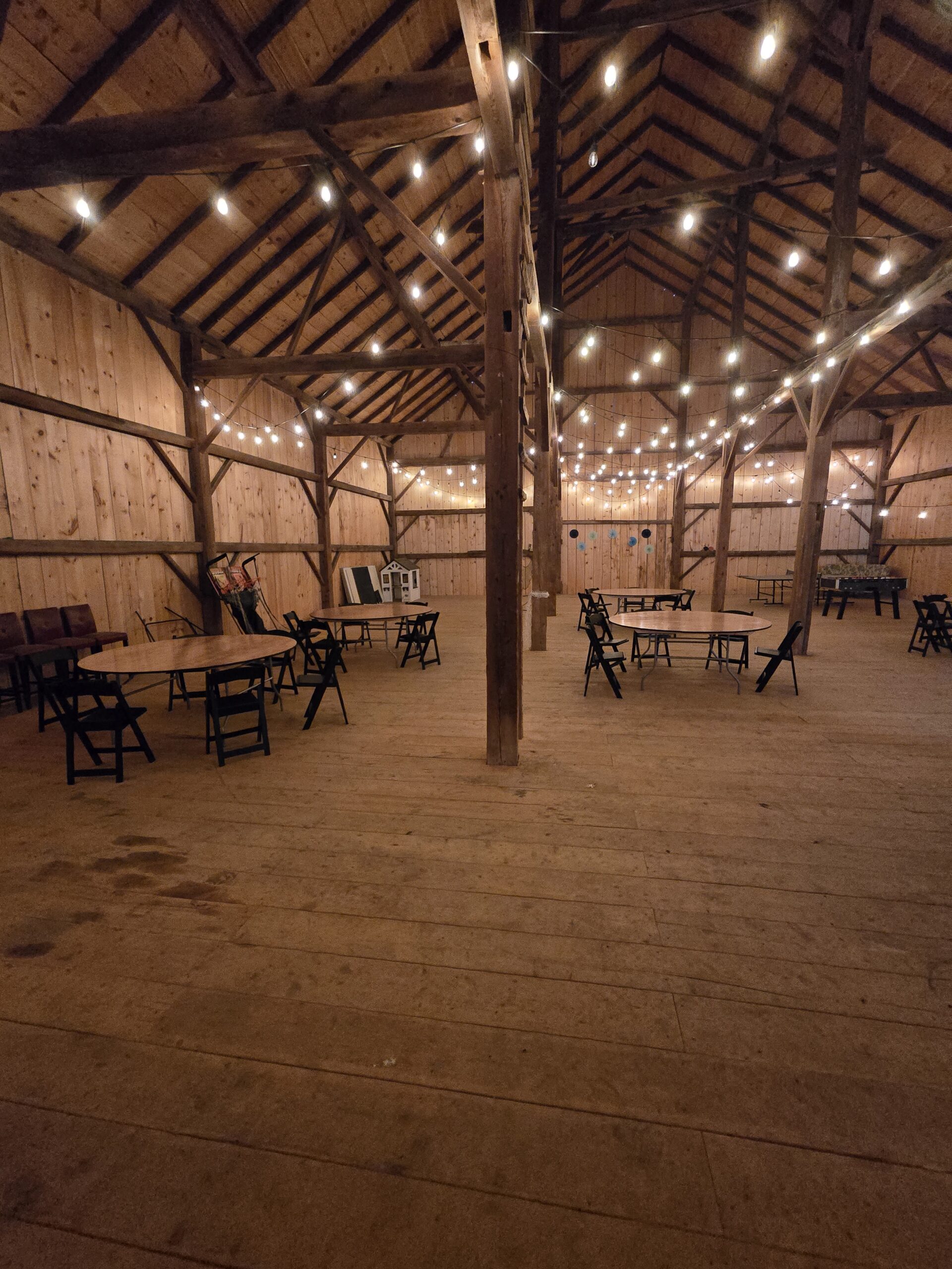 Rustic barn hall set with round tables and glowing string lights