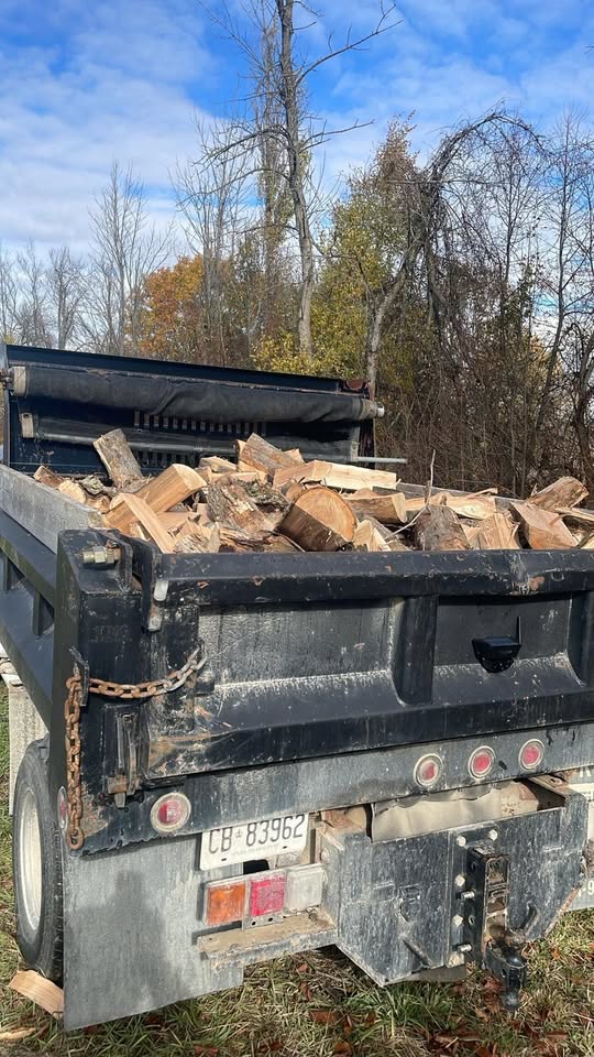 Split firewood loaded in the bed of a black dump truck