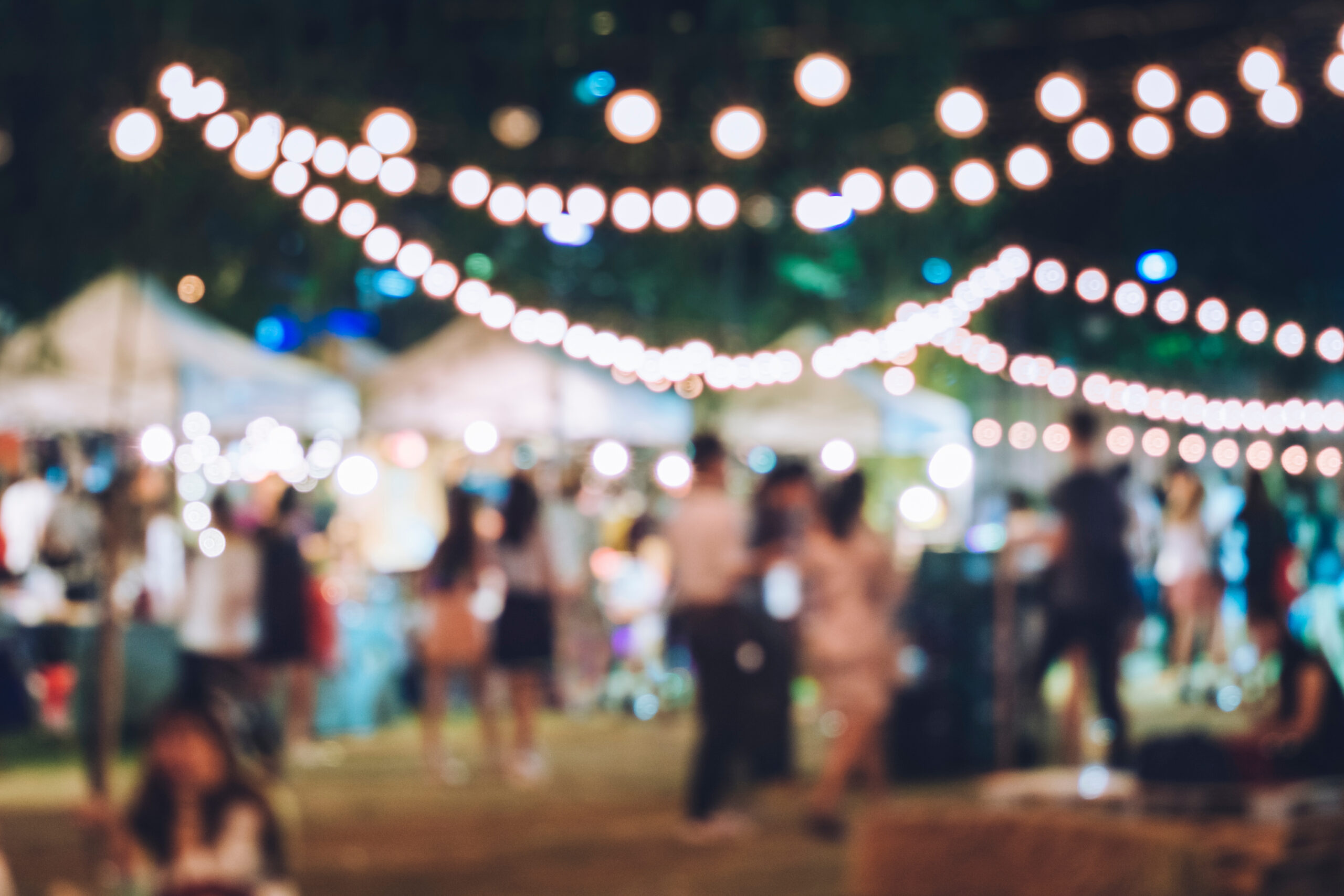 Blurred evening festival crowd under strings of glowing lights