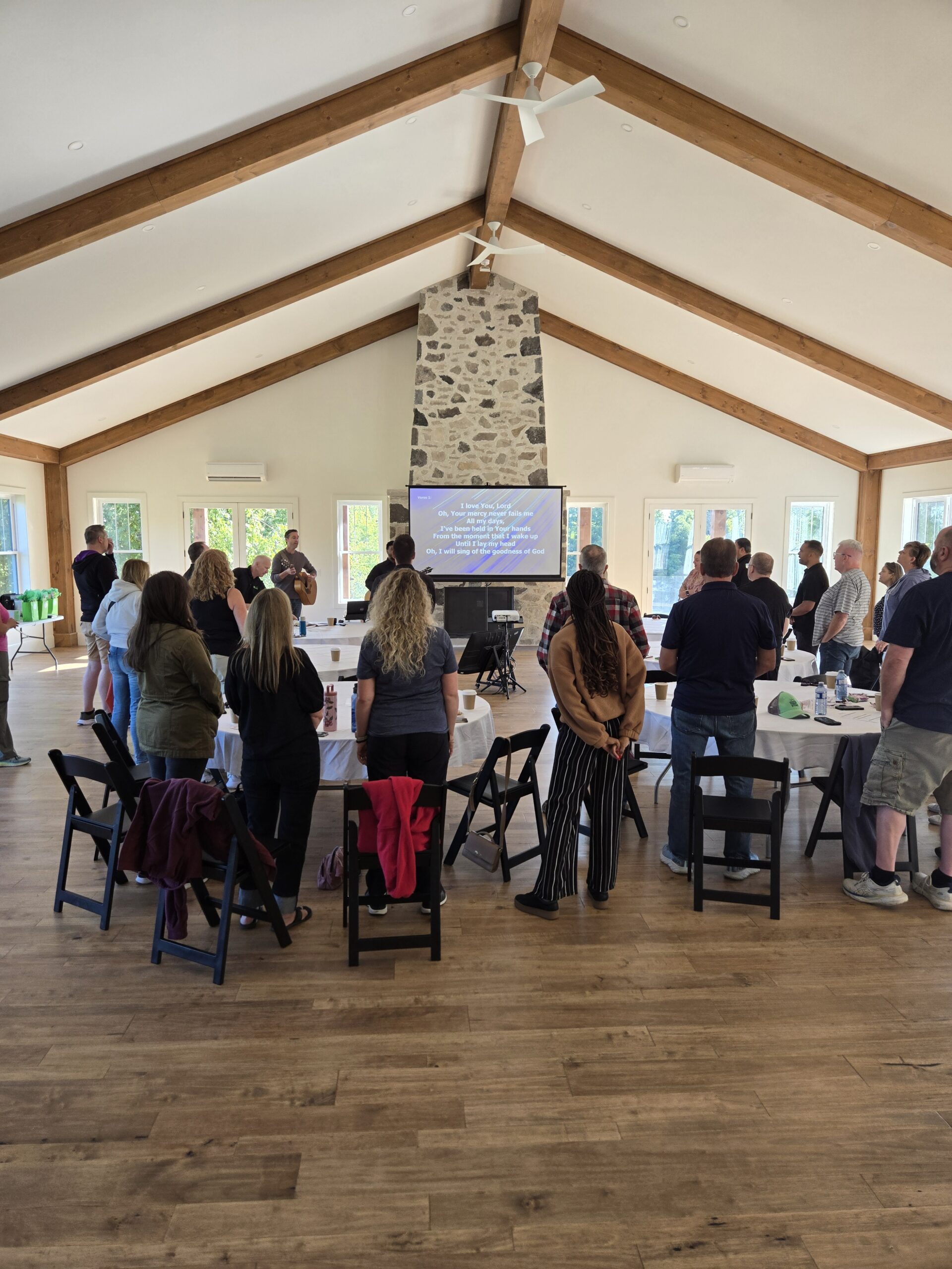 Group standing in worship facing screen inside the timber-beamed conference centre