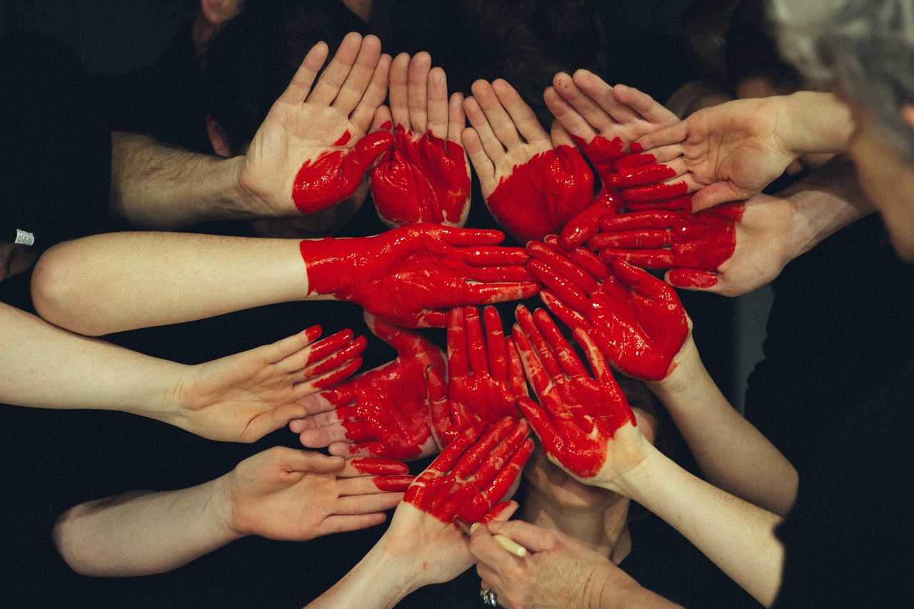 Many hands painted red pressed together forming a heart shape