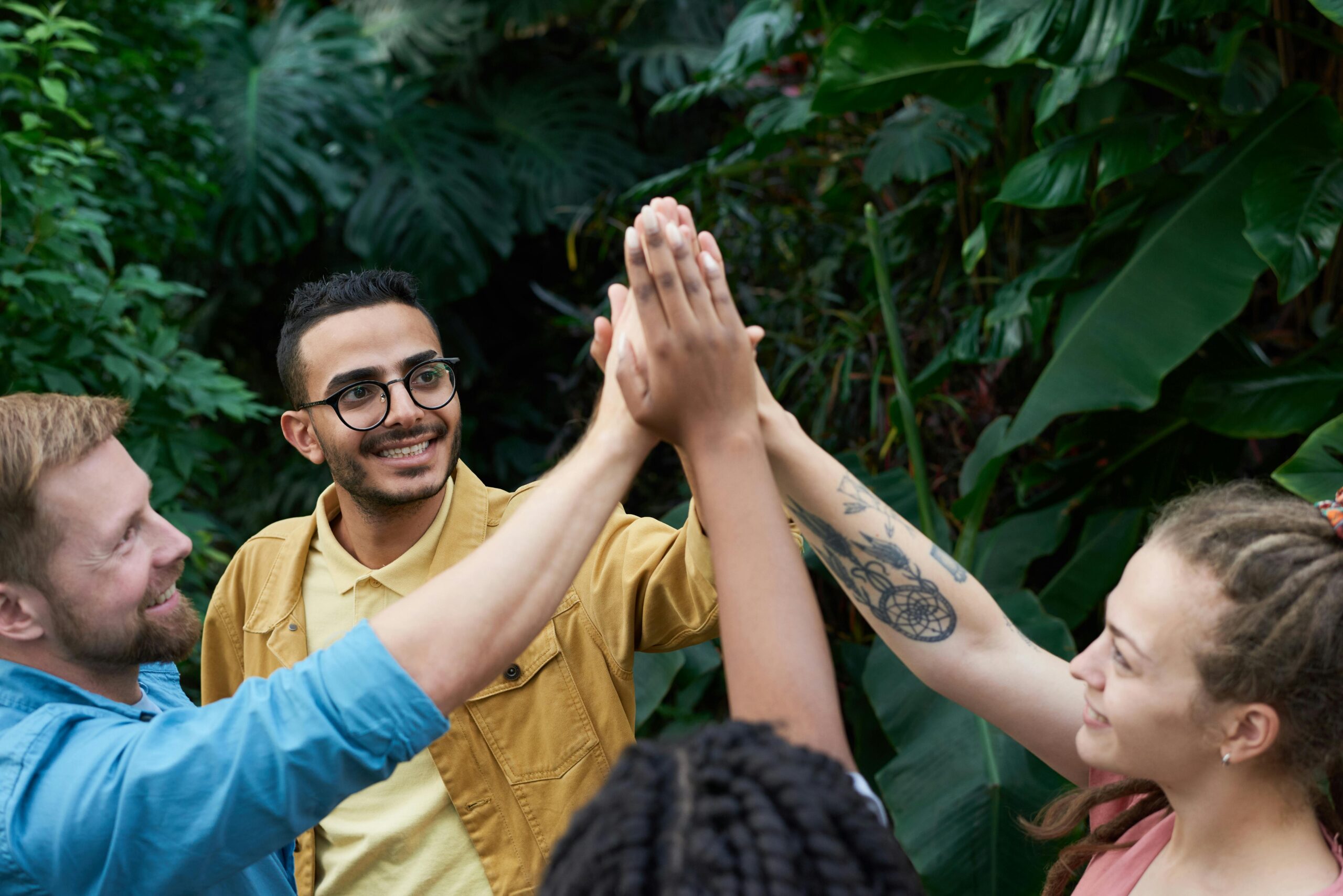 Diverse team members joining hands in a group high-five outdoors